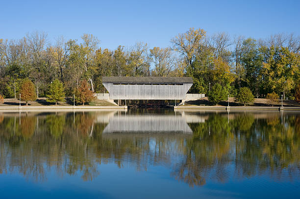 Brownsville Covered Bridge Reflection "The Brownsville Covered Bridge, located in Mill Race Park in Columbus, Indiana, was originally moved from Union County, Indiana to Eagle Creek, where it was put into storage until its rejuvenation at Mill Race Park.  It is considered the longest single lane covered bridge in Indiana." indiana covered bridge stock pictures, royalty-free photos & images