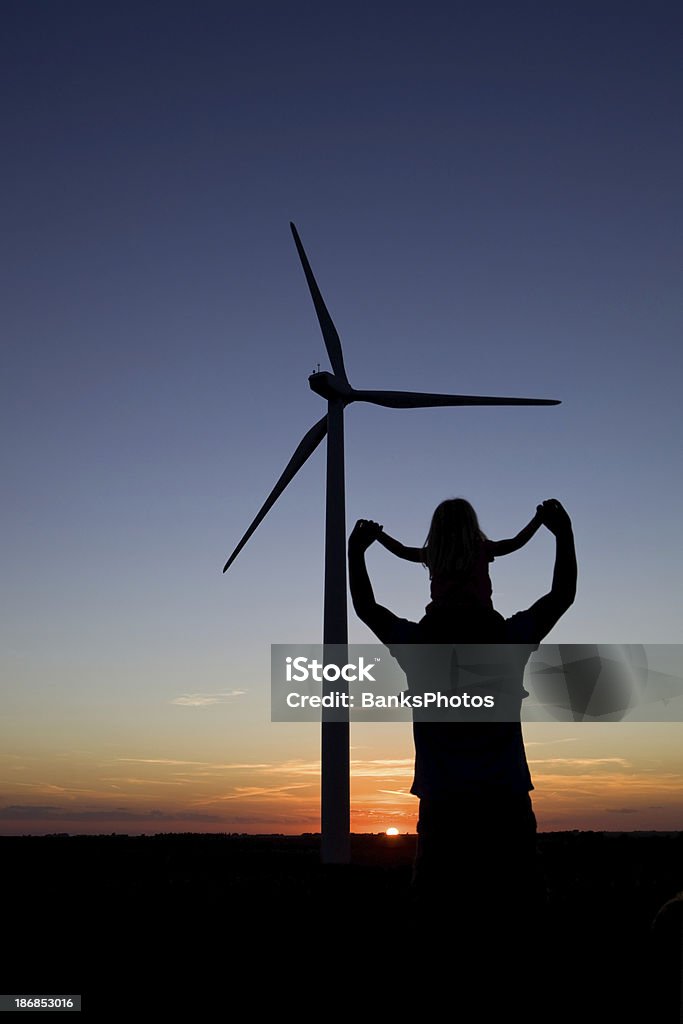 Dziecko dziewczynka na tata's ramiona w pobliżu turbin wiatrowych o zachodzie słońca - Zbiór zdjęć royalty-free (Dziecko)