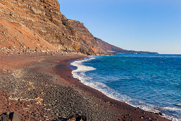 Playa del Verodal is the biggest beach of El Hierro and the only one with natural reddish sand. Behind it there is a huge rocky cliff with thousand of coloured shades, in front of it the sea is clear, but sometimes dangerous for swimming. Nearby is a picnic area. El Hierro, Canary Islands, Spain. Canon EOS 5D Mark II