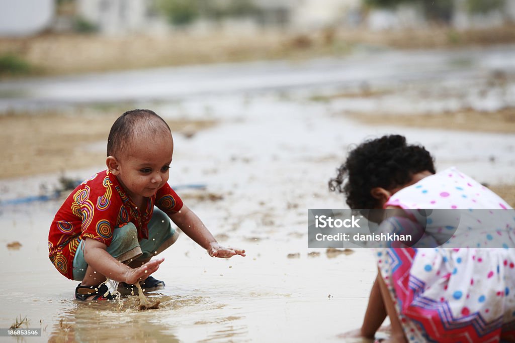 I bambini giocano la libertà dell'acqua piovana Pozzanghera Schizzare - Foto stock royalty-free di 2-3 anni