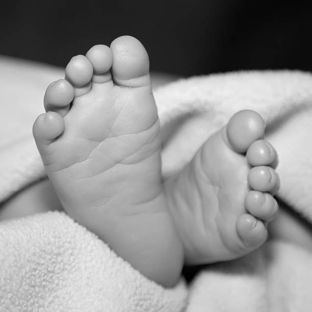 ブラックとホワイトの赤ちゃんの足のクローズアップ - human foot baby black and white newborn ストックフォトと画像