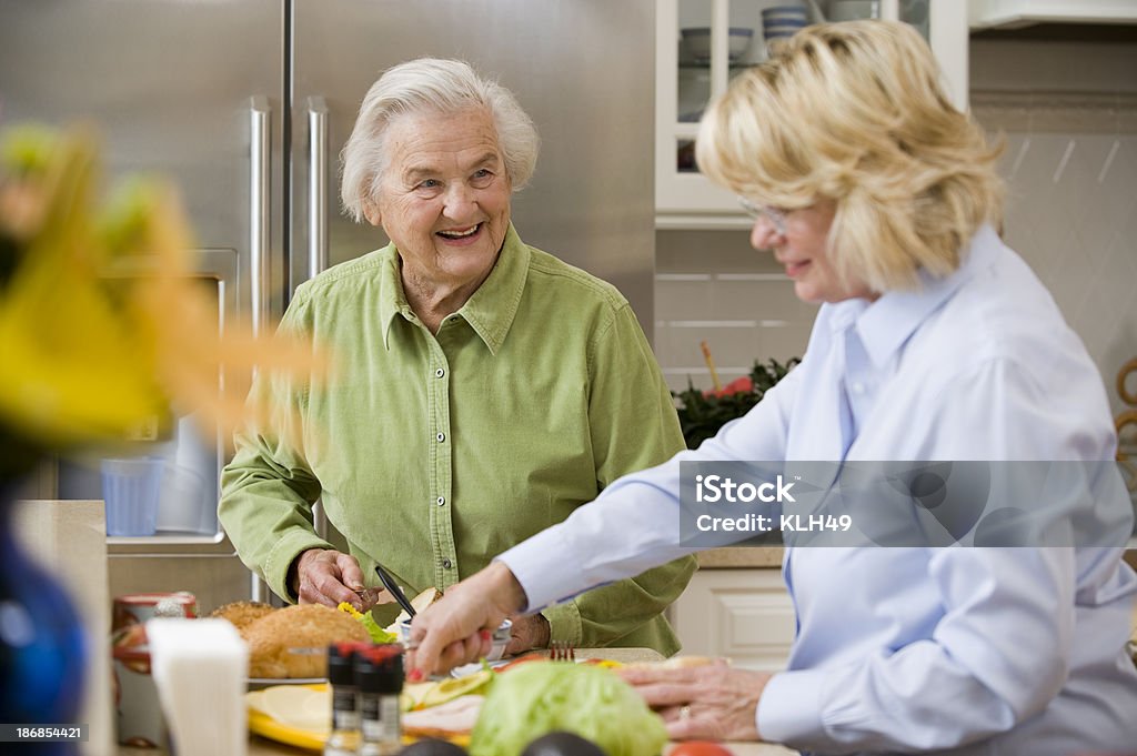 Uśmiech Starszy Dama z przyjacielem w kuchni - Zbiór zdjęć royalty-free (Gotować)