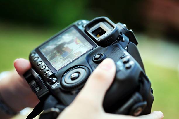 fancy digital camera with controls holding a modern dslr - controlling the image and adjustment urlaubsbilder stock pictures, royalty-free photos & images