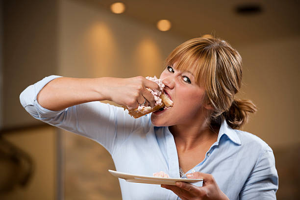 istock Young woman eating piece of cake with both hands 186856309
