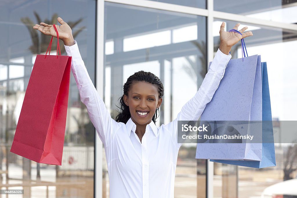 Satisfied costumer with shopping bags "Attractive young african decent woman holding up her shopping bags, staying outside of mall.Similar images preview:" 20-24 Years Stock Photo