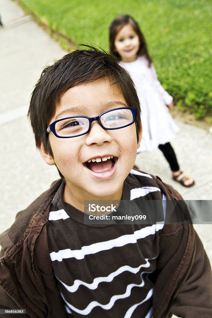 Niño atractivo en el parque con hermana detrás - Foto de stock de Aire libre libre de derechos