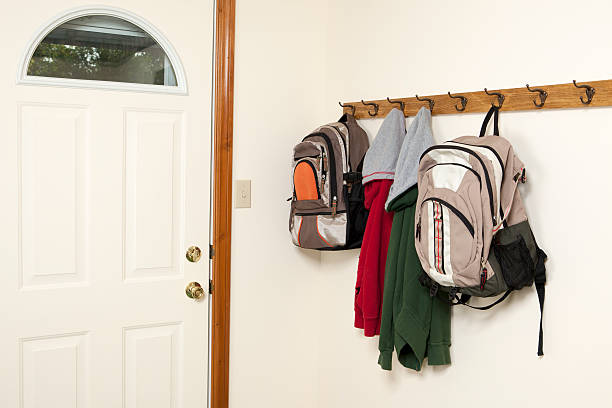 Backpacks and Jackets by Backdoor Two backpacks and jackets hanging on a wall rack by the back door.Please also see: coat hook photos stock pictures, royalty-free photos & images