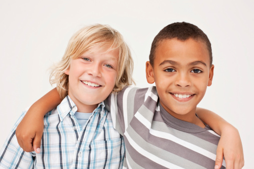 Portrait of a two cute little male friends smiling together on white