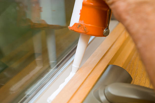 Weather Seal Caulk being applied to Window Frame  winterizing stock pictures, royalty-free photos & images