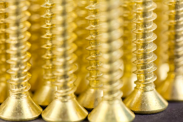 Macro image of  an array of brass wood screws. The sharp point on the end is designed to attach together two pieces of wood.