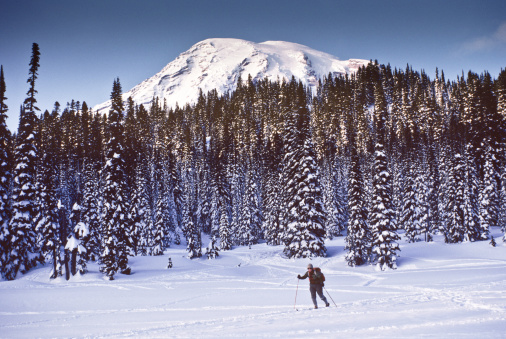 At 14,410' above sea level, Mount Rainier dominates the landscape of the Puget Sound region. Mount Rainier is the highest point in Washington State, and is also the most glaciated mountain in the continental United States. This picture of a cross country skier was taken from Reflection Lakes in Mount Rainier National Park, Washington State, USA.