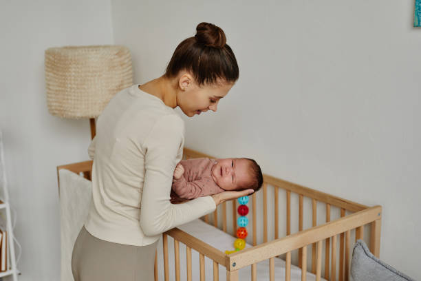 istock Caring Mother Putting Baby into Crib 1868598608