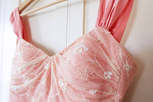 Close up of pink wedding dress hanging on white door Close up of a pink wedding dress haning against a white door. prom dress stock pictures, royalty-free photos & images