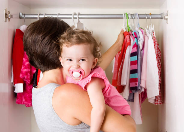 Smiling baby on the shoulders of woman looking at closet stock photo