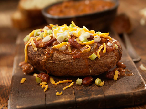 Baked Potato Topped with Chili "Baked Potato Topped with Chili, Sour Cream, Green Onions and Cheddar Cheese with Garlic Bread -Photographed on Hasselblad H3D-39mb Camera" baked potato sour cream stock pictures, royalty-free photos & images