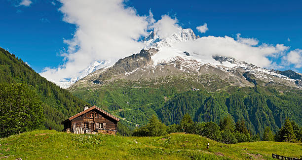 Idyllic Alpine chalet summer mountain meadow panorama Alps Traditional wooden Alpine chalet in idyllic wildflower meadow overlooked by snow capped peaks and dramatic mountain scenery under panoramic blue summer skies. ProPhoto RGB profile for maximum color fidelity and gamut. mont blanc photos stock pictures, royalty-free photos & images