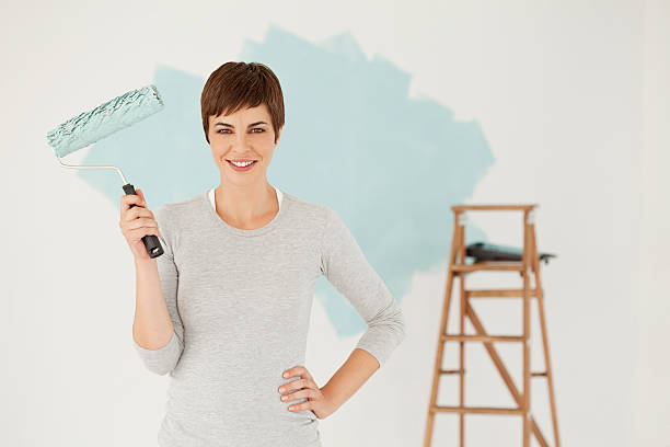 istock Young Woman Smiling Holding Paint Roller 186861874