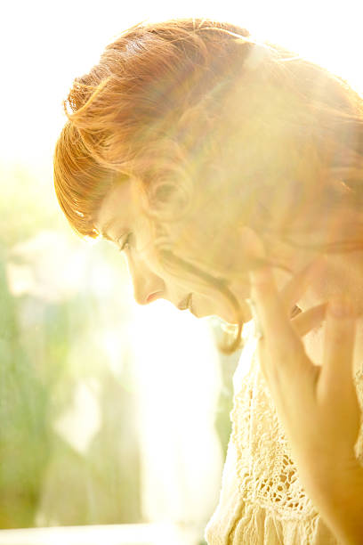 istock Redhead woman backlit by sun with hand on glass window 186862278