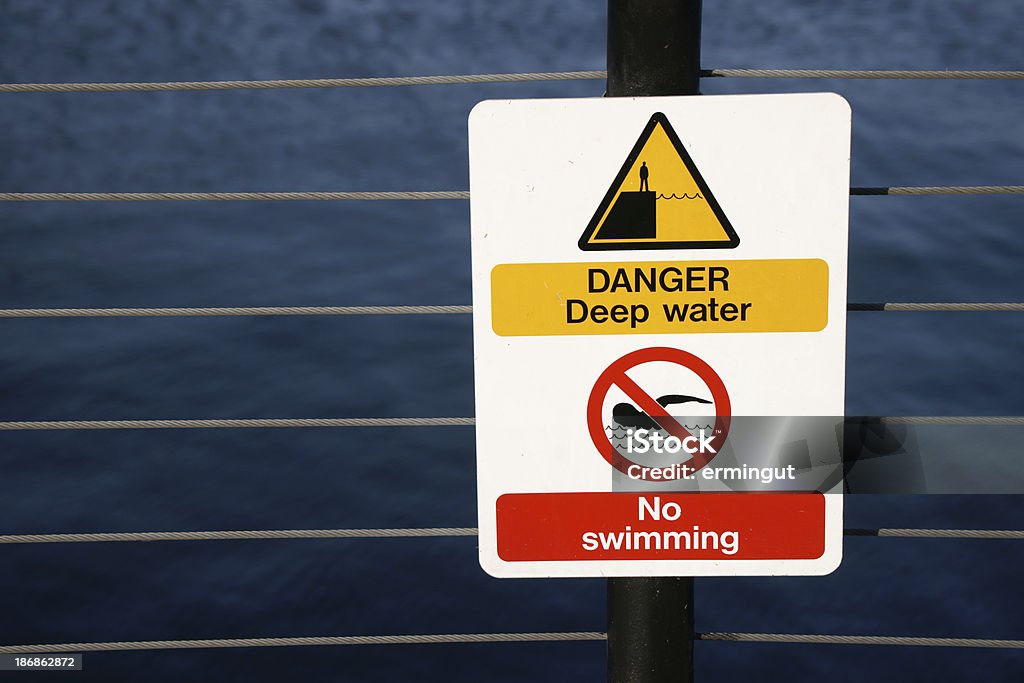 Placa de proibido nadar No muro contra água escura - Foto de stock de Abstrato royalty-free
