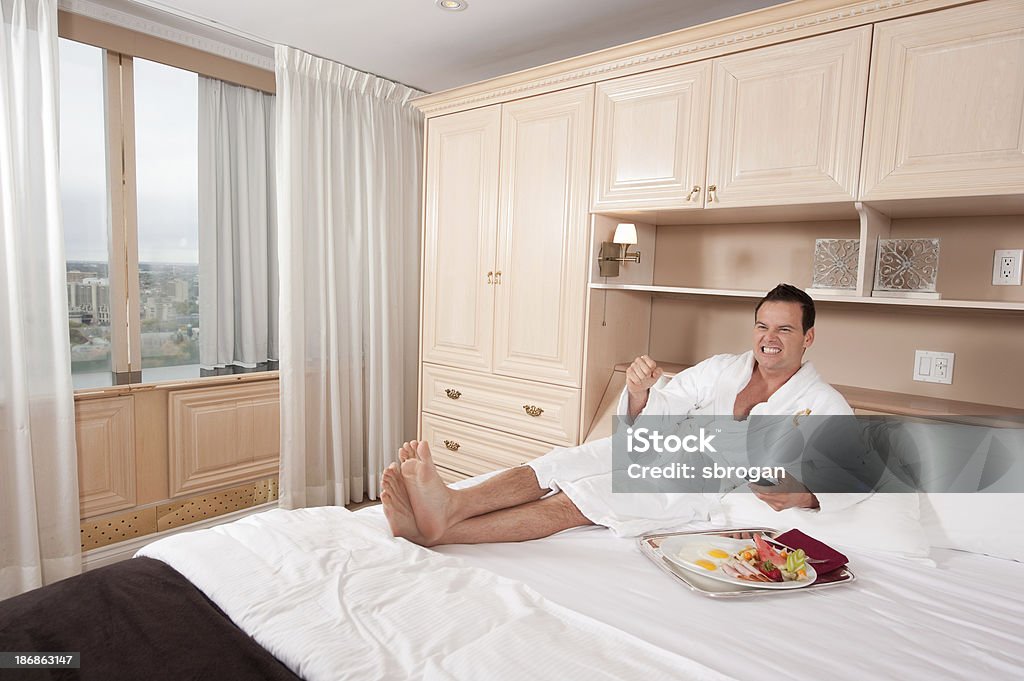 Uomo tifo la tv in un hotel elegante suite - Foto stock royalty-free di Accappatoio