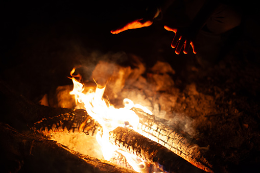 Human Hands Heating Up Close to a Camp Fire in Winter Darkness