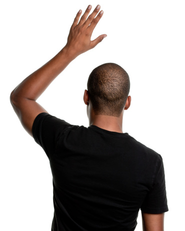Rear-view of a young African-American man raising his hand.