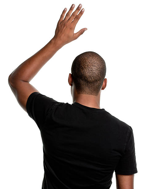 Rear View of Young Man, Hand Raised Asking Question Rear-view of a young African-American man raising his hand. back of head photos stock pictures, royalty-free photos & images