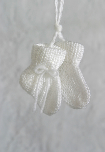 A pair of white baby booties waiting for their new arrival.