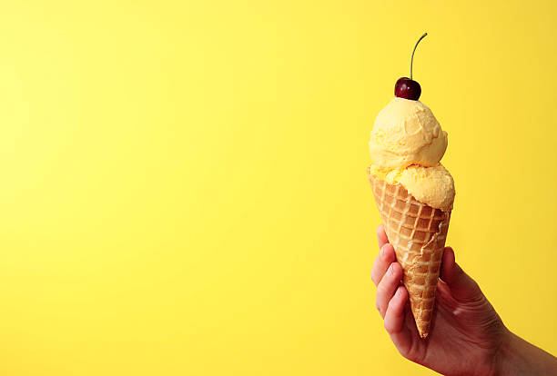 A hand holding adouble scoop ice cream cone.