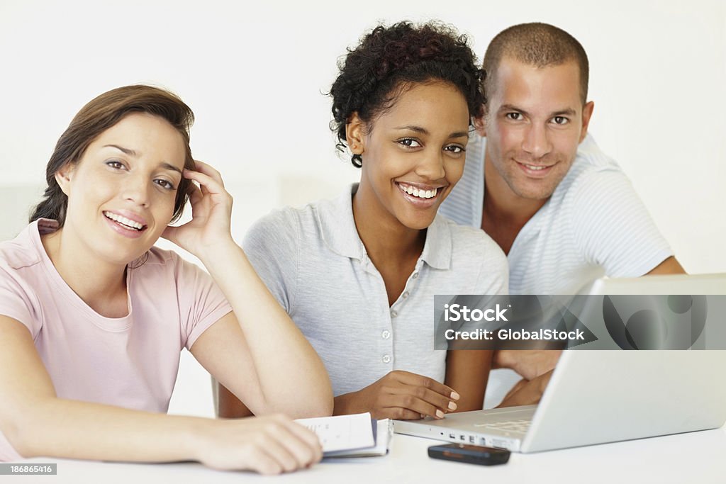 Três jovens estudantes felizes usando um computador laptop - Foto de stock de Adulto royalty-free