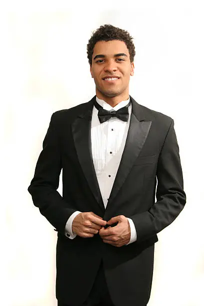 Young minority guy in a tuxedo isolated on white