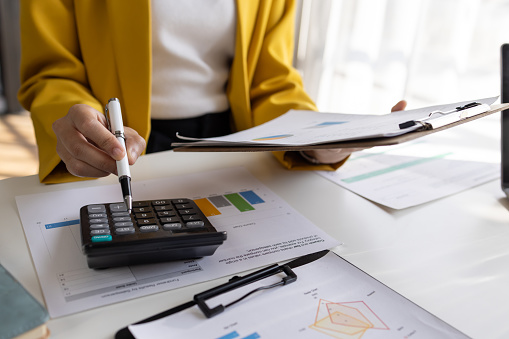 business women working on desk office with using a calculator to calculate the numbers tax, finance accountingresearch or financial strategy in company concept