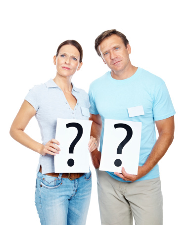 Portrait of a mature couple with question mark sign against white background