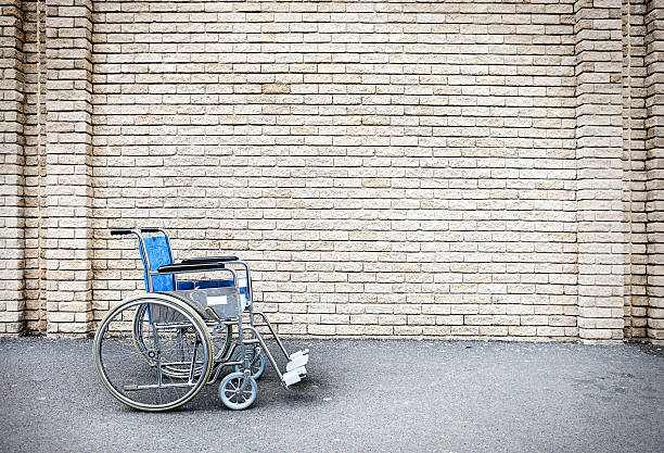 Lone wheelchair parked outside next to a blank brick wall