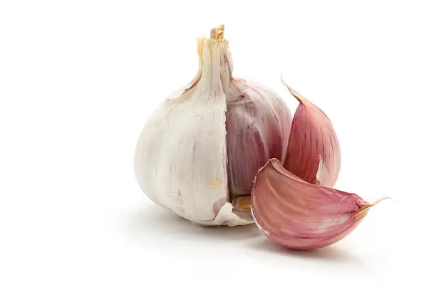 "A garlic bulb with two cloves split off, isolated on a white background."