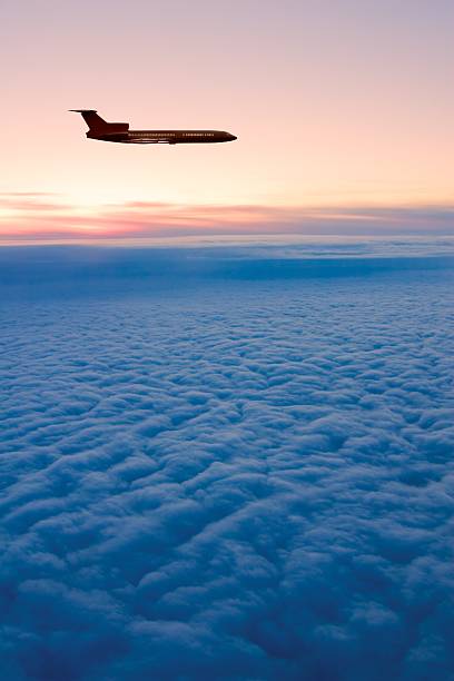 Sunrise flight Daybreak. Passenger airplane silhouette on the morning-glow background. planes flying overhead stock pictures, royalty-free photos & images
