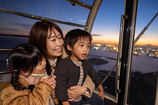 Family looking at view from Ferris Wheel at sunset time