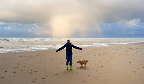 istock girl standing on beach with dog and approaching snow storm 186868856