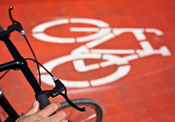 Cycle line sign on red ground with handlebar of cyclist in the foreground. Selective focus on hand.Some more bicycles in the lightbox: