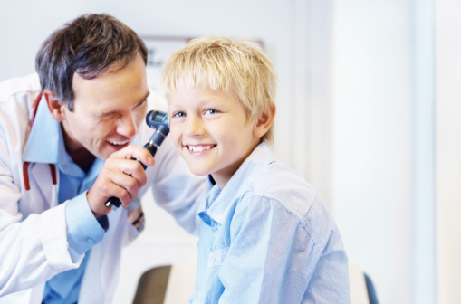 Handsome mature doctor checking patient's ears in clinic
