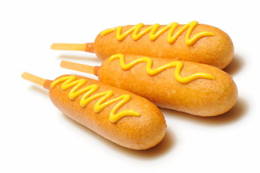 Three corn dogs with yellow mustard isolated on white. More pictures in lightbox...