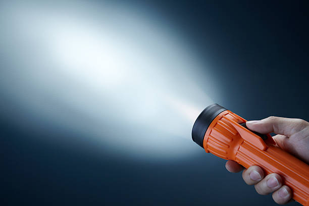 Person holdings orange flashlight searching in darkness flashlight's beam pointing at wall with copy space flashlight stock pictures, royalty-free photos & images