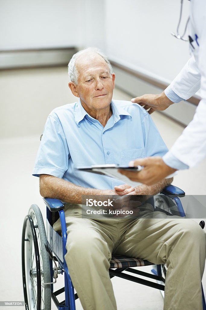 Médico mostrando informes a un hombre para personas con discapacidades - Foto de stock de 50-59 años libre de derechos