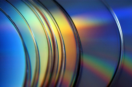 Compact Discs reflecting blues and golds stacked on top of each other