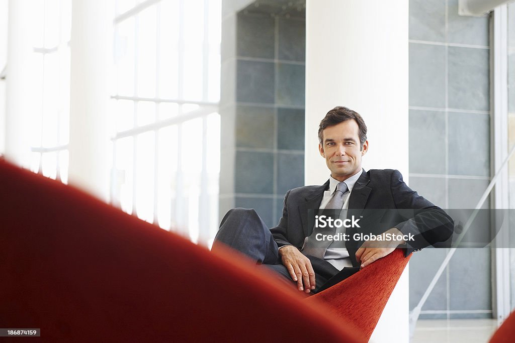 魅力的なビジネスの男性のシッティングエリアと自信を持って笑う - 赤のロイヤリティフリーストックフォト