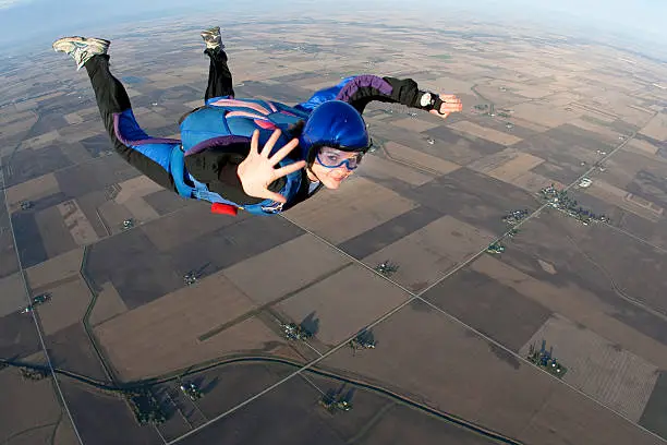 Photo of Young lady skydiving whilst mid-air waving to camera
