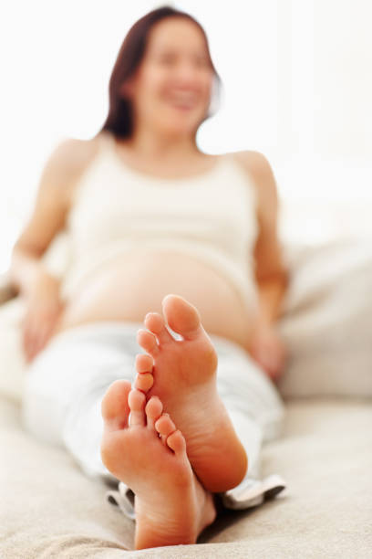 Beautiful pregnant woman relaxing on couch with focus on feet