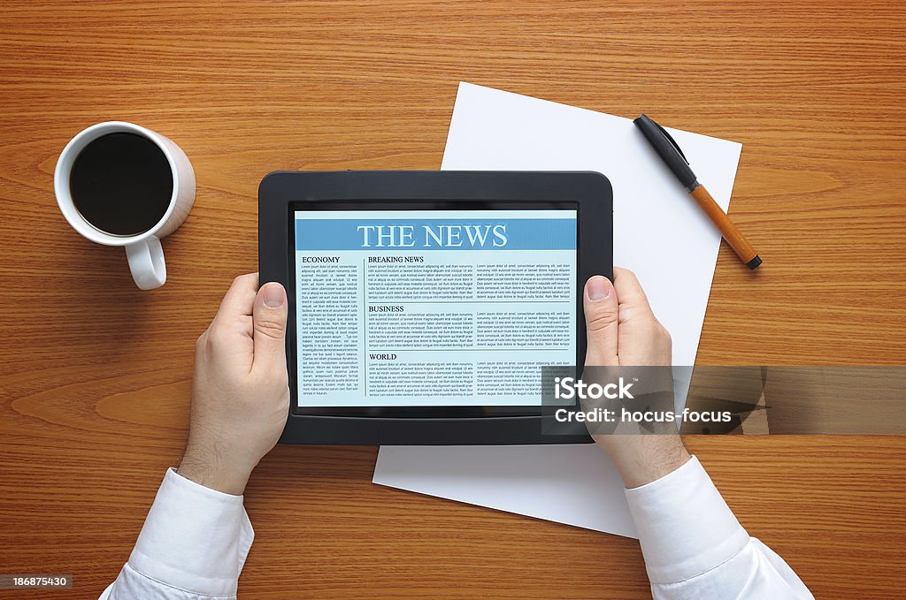 Reading news with tablet pc Businessman reading news with tablet pc on office desk. Reading Stock Photo