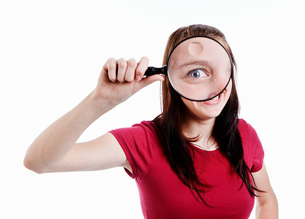 istock Zany brunette looks through magnifying glass at camera 186875514