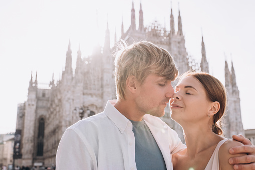 A couple of lovers, a man and a woman, hugging against the Duomo in Milan, Lombardy, Italy